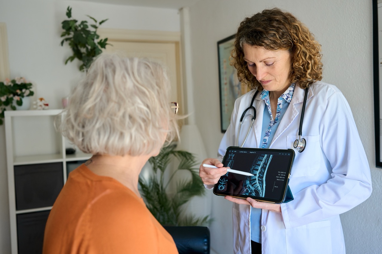 Doctor explaining a spinal mri scan on a digital tablet to a senior patient during a medical consultation in clinic